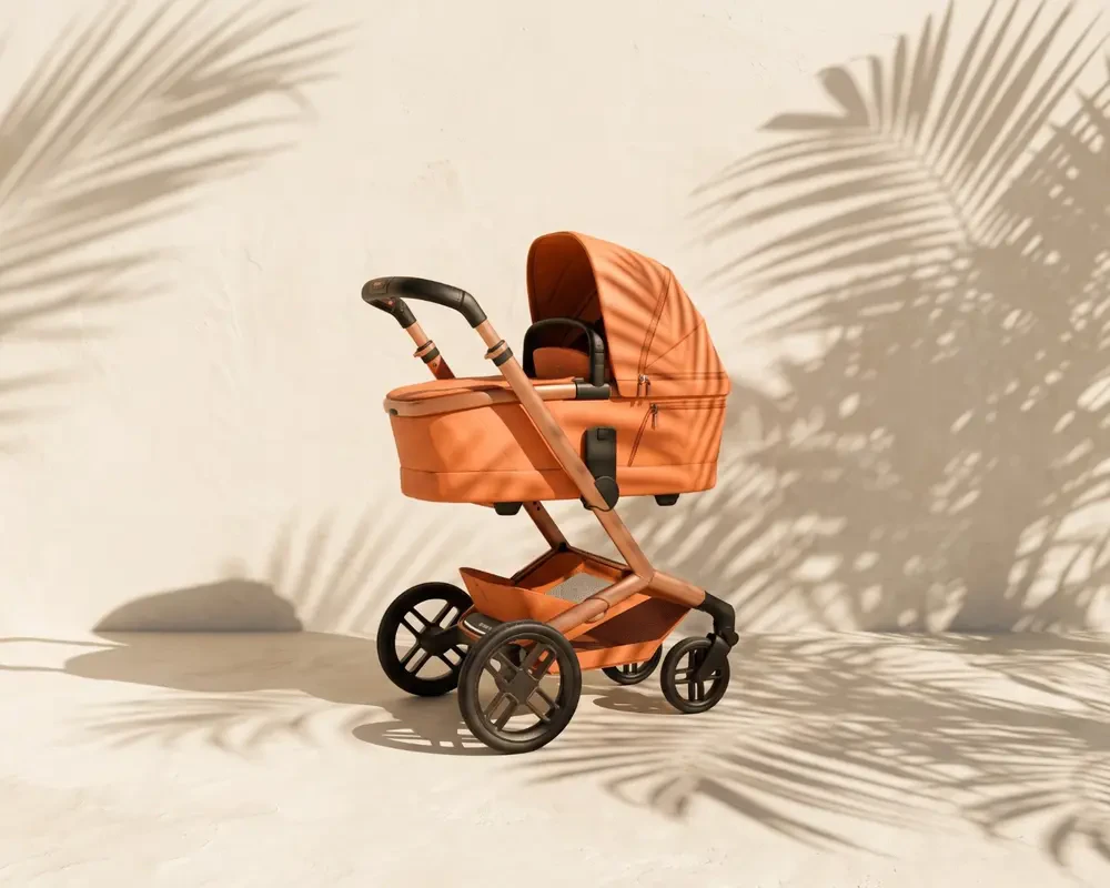 Stroller with carrycot in terracotta against a sunlit plaster wall, palm-leaf shadows falling across it and the floor